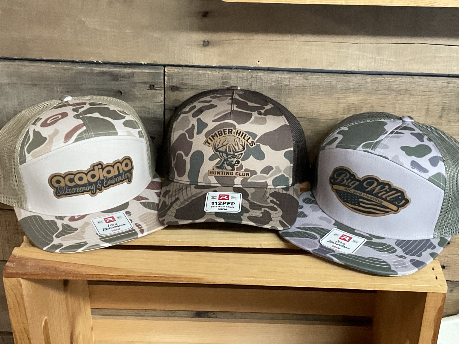 Three camouflage hats with custom logo patches