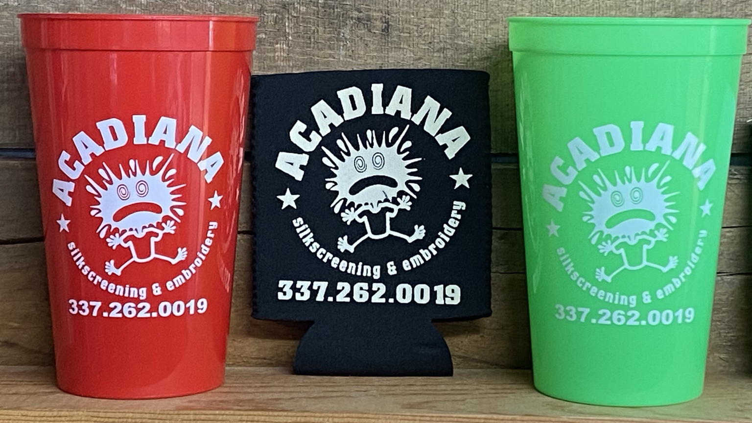 Red and green Acadiana cups and black koozie