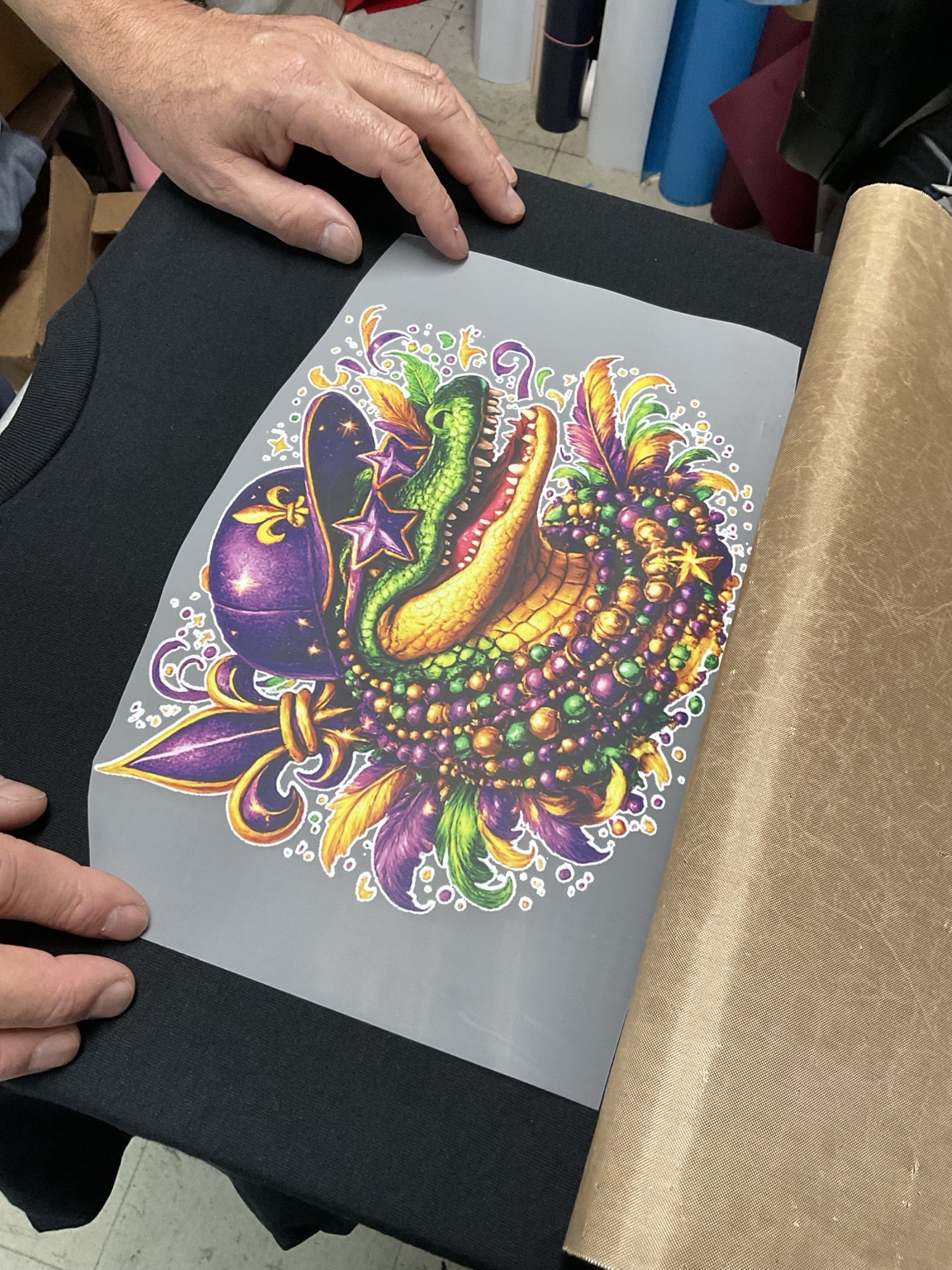 Colorful alligator DTF transfer being positioned on a black shirt