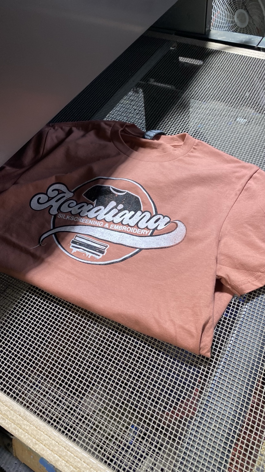 Acadiana's printed retro logo shirt on the shop conveyor dryer